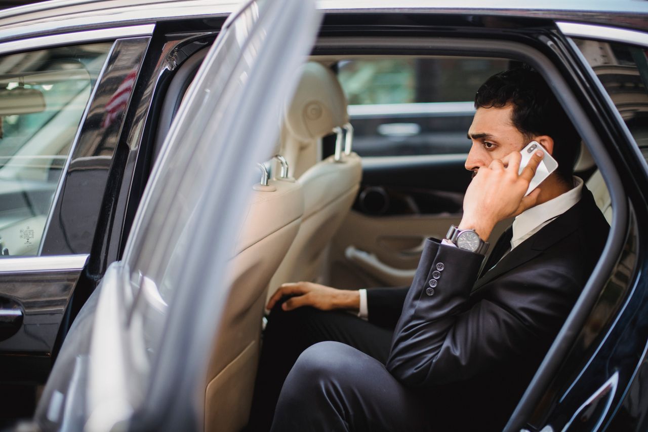 A propos Professional man in suit making a phone call while sitting in a vehicle.